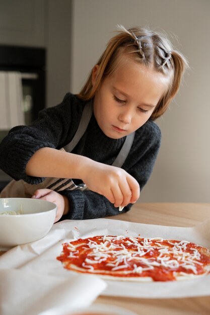 Ragazza di vista frontale che cucina pizza