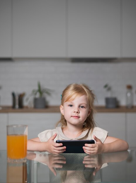 Ragazza di vista frontale che tiene cellulare a casa