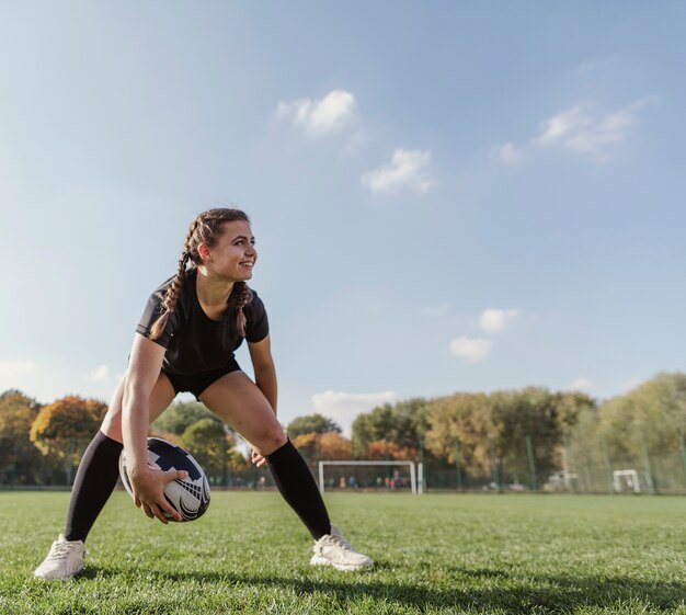 Ragazza di vista frontale che tiene una palla di rugby con lo spazio della copia