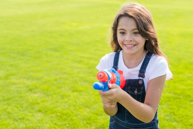 Ragazza di vista frontale che tiene una pistola ad acqua