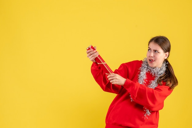 Ragazza di vista frontale con il maglione rosso che tiene il popper del partito