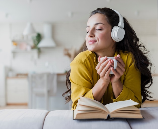 Ragazza di vista frontale con le cuffie e il libro