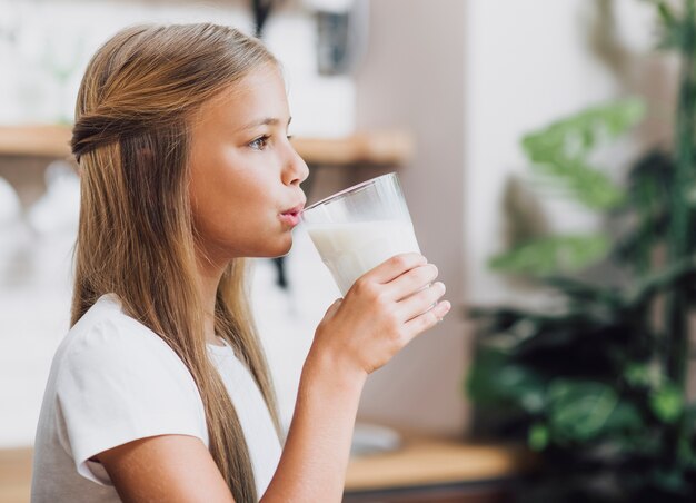 Ragazza di vista laterale che beve un bicchiere di latte