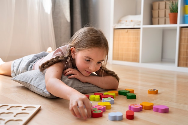 Ragazza di vista laterale che fa puzzle sul pavimento