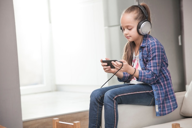 Ragazza di vista laterale in cuffie tramite smartphone