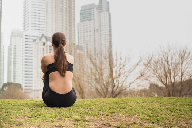 Ragazza di vista posteriore che si siede sull'erba