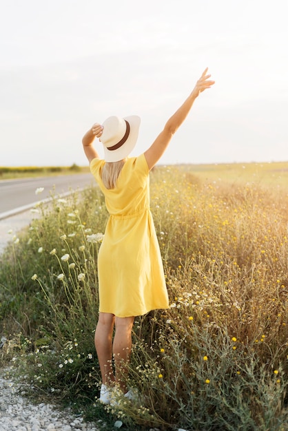 Ragazza di vista posteriore con il cappello che gode della natura