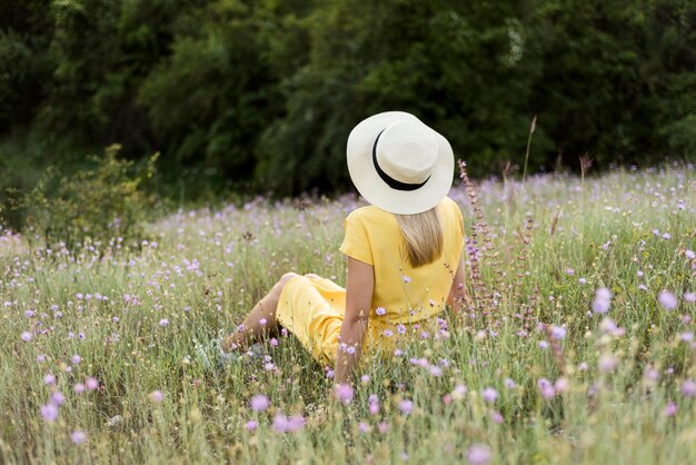 Ragazza di vista posteriore con il cappello che si distende all'aperto