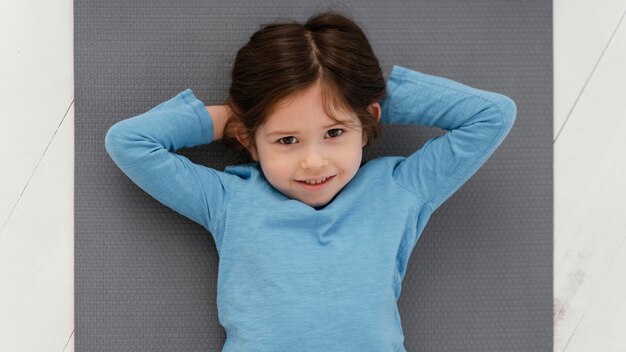 Ragazza di vista superiore che pone sulla stuoia