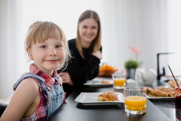 Ragazza dolce che guarda l&#39;obbiettivo durante la colazione