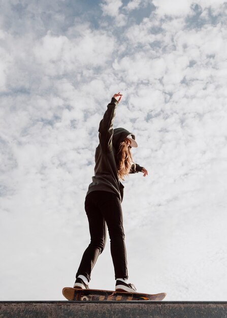 Ragazza e cielo del pattinatore di vista bassa