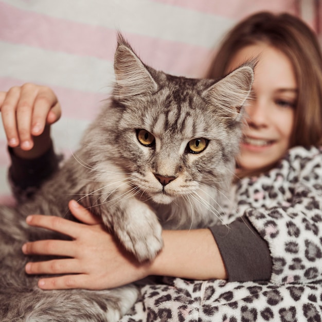 Ragazza e gatto che si siedono nel letto