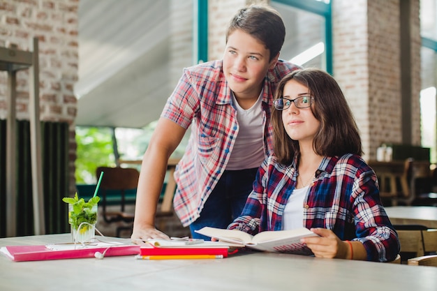 Ragazza e ragazzo che guarda via con i libri