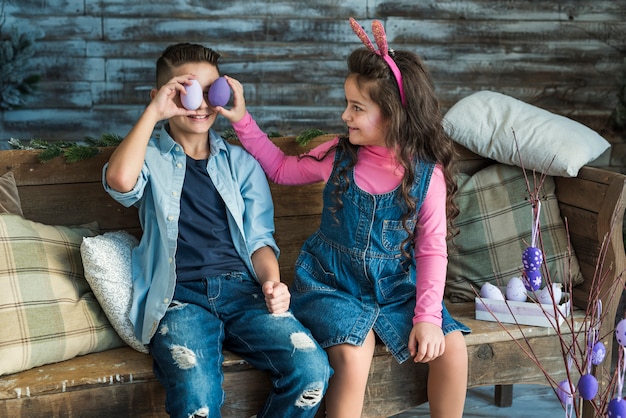 Ragazza e ragazzo tenendo le uova di Pasqua agli occhi