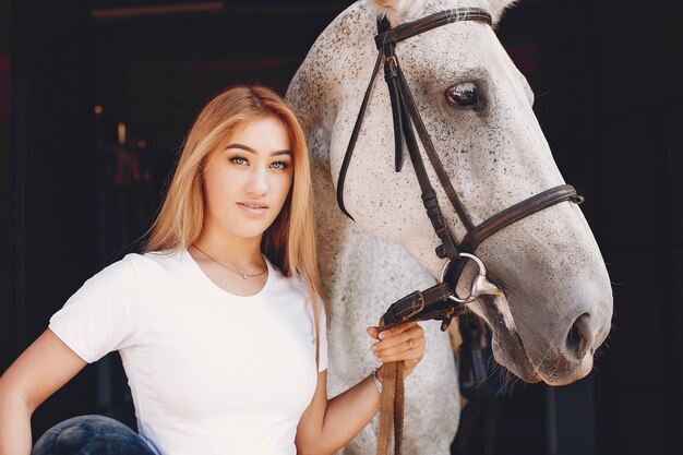 Ragazza elegante in una fattoria con un cavallo