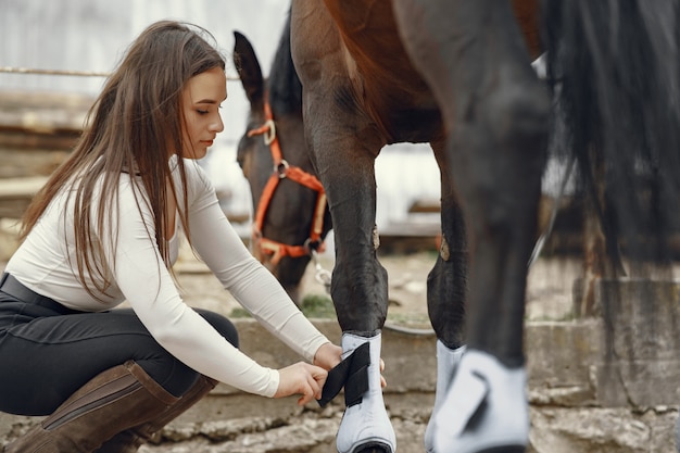 Ragazza elegante in una fattoria con un cavallo