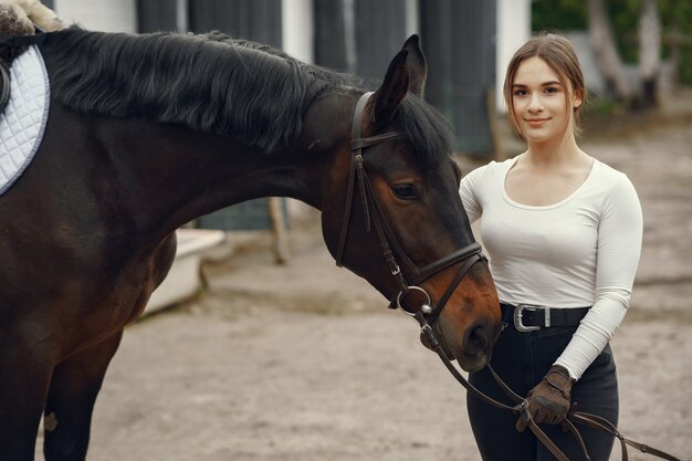 Ragazza elegante in una fattoria con un cavallo