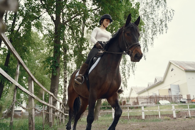 Ragazza elegante in una fattoria con un cavallo