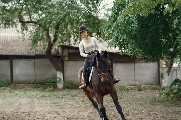 Ragazza elegante in una fattoria con un cavallo