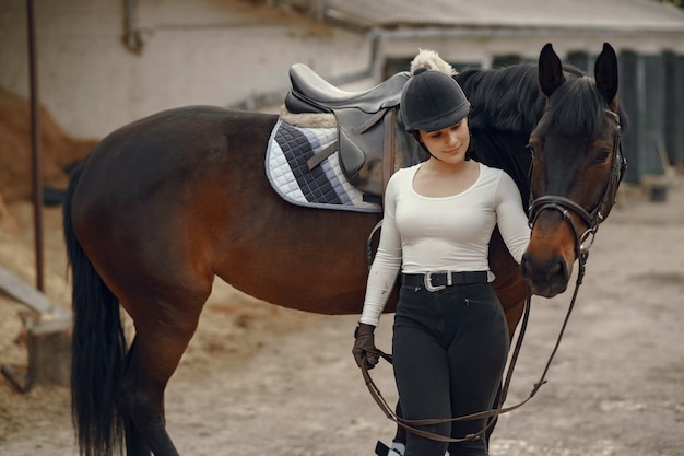 Ragazza elegante in una fattoria con un cavallo