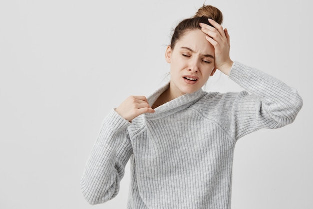 Ragazza esaurita che tiene la sua testa con gli occhi chiusi che sono caldi. Assistente di ufficio femminile che soffre di febbre e temperatura ha bisogno di aria fresca. Concetto di salute