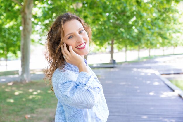 Ragazza felice allegra che parla sul telefono cellulare