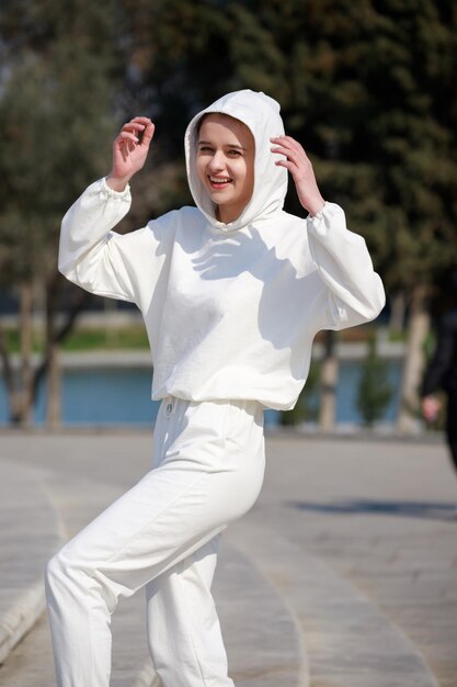 Ragazza felice che indossa felpa con cappuccio e cammina al parco Foto di alta qualità