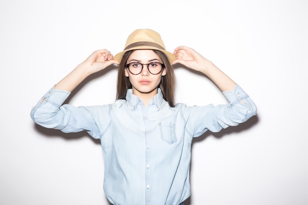 Ragazza felice che posa in cappello di paglia, camicetta estiva rosa e pantaloncini blu.