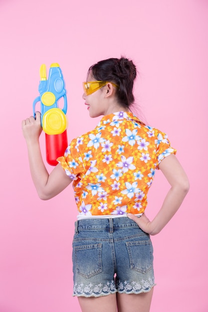 Ragazza felice che tiene una pistola a acqua rosa del fondo.