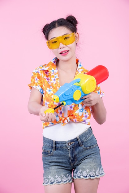 Ragazza felice che tiene una pistola a acqua rosa del fondo.