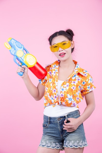 Ragazza felice che tiene una pistola a acqua rosa del fondo.