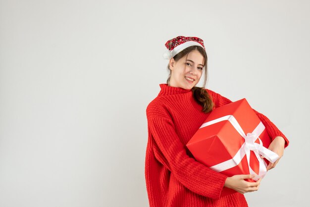 ragazza felice con il cappello della santa che tiene il suo regalo di natale su bianco