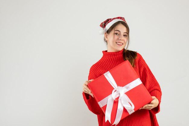 ragazza felice con il cappello della santa che tiene il suo regalo di natale su bianco