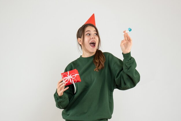 ragazza felice con il tappo del partito che tiene il suo regalo di Natale e rumorista su bianco