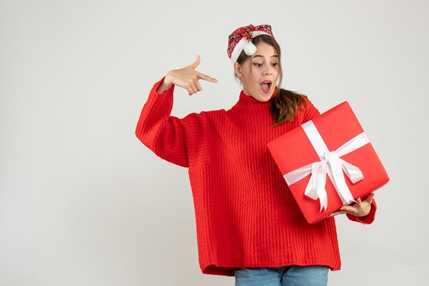 ragazza felice con santa cappello che punta al suo regalo su bianco