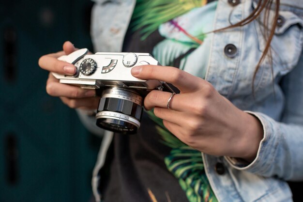 Ragazza felice dei pantaloni a vita bassa che fa foto con la retro macchina fotografica sulla via della città. Concetto di viaggio. Colpire