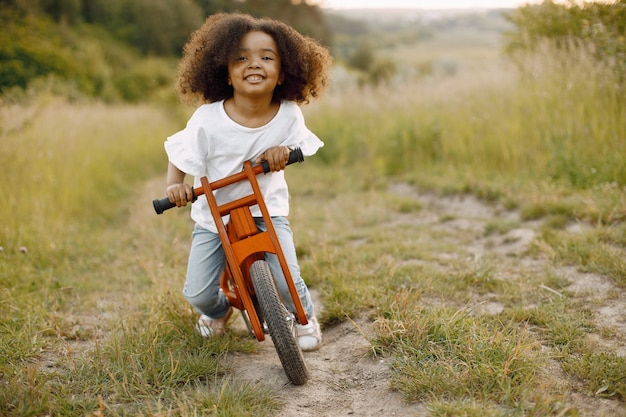 Ragazza felice del bambino che guida bici rossa. Il bambino impara ad andare in bicicletta