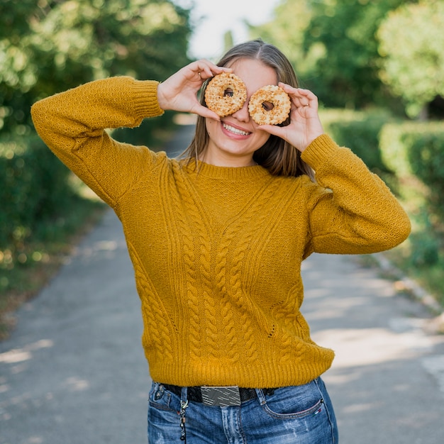 Ragazza felice del colpo medio con le ciambelle all'aperto