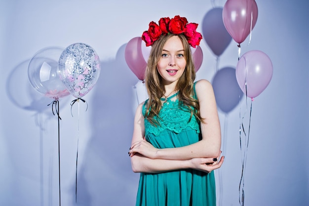 Ragazza felice in abito turchese verde e corona con palloncini colorati isolati su bianco Celebrando il tema del compleanno