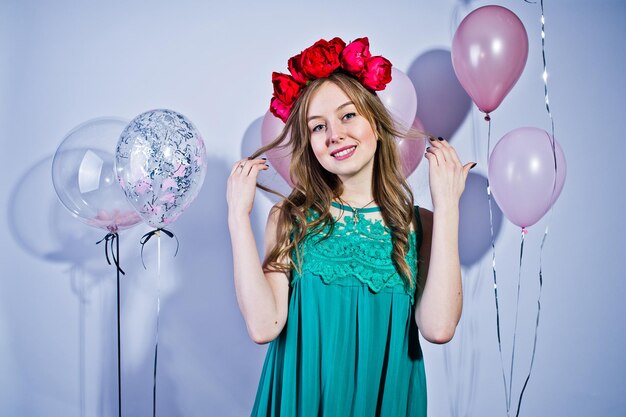 Ragazza felice in abito turchese verde e corona con palloncini colorati isolati su bianco Celebrando il tema del compleanno