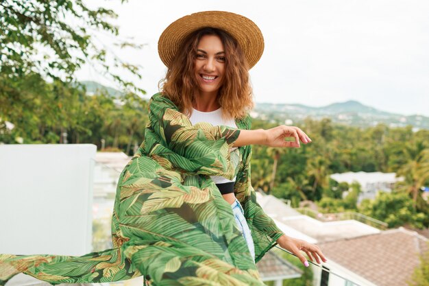 Ragazza felice in cappello di paglia ballare e divertirsi sulla terrazza.