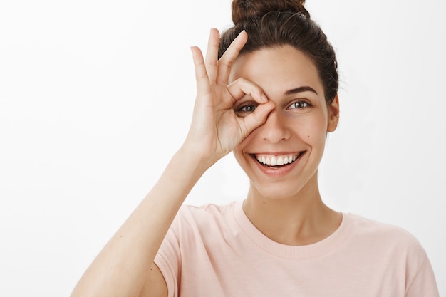 Ragazza felice vaga che posa contro il muro bianco