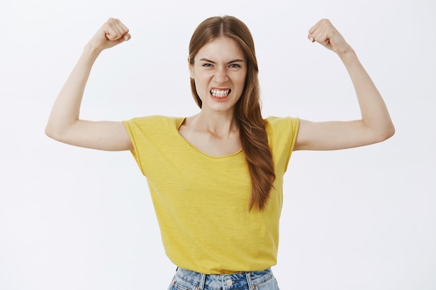 Ragazza forte e potente che flette i bicipiti, mostrando la sua forza