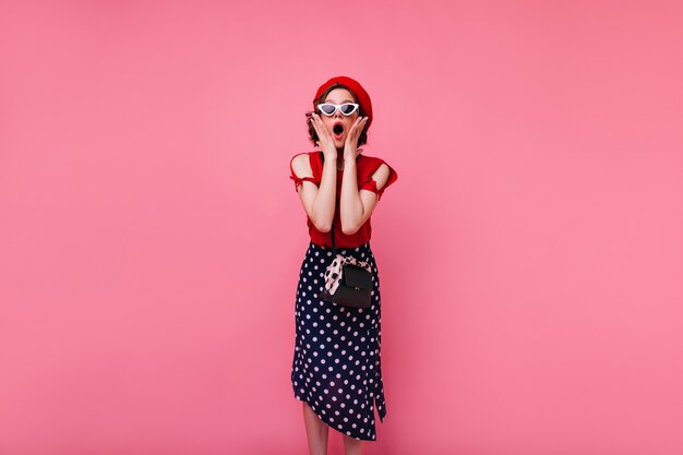 Ragazza francese dai capelli corti sorpresa in posa. Foto dell'interno della donna alla moda in gonna lunga che esprime stupore.