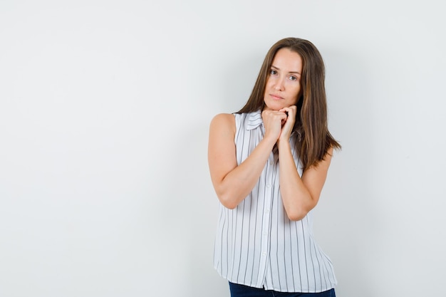 Ragazza giovane appoggiando il mento sul pugno in t-shirt, jeans, vista frontale.