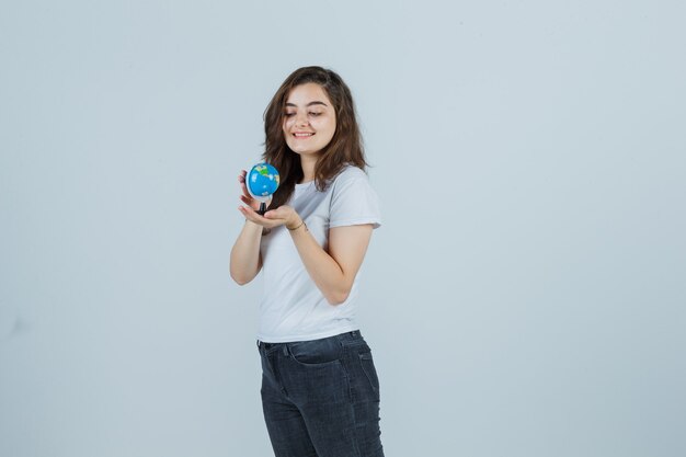 Ragazza giovane con globo in t-shirt, jeans e carino, vista frontale.