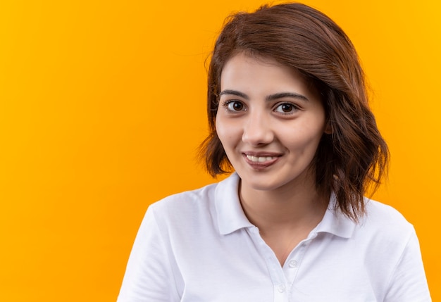 Ragazza giovane con i capelli corti che indossa la maglietta di polo che guarda l'obbiettivo con il sorriso sul viso