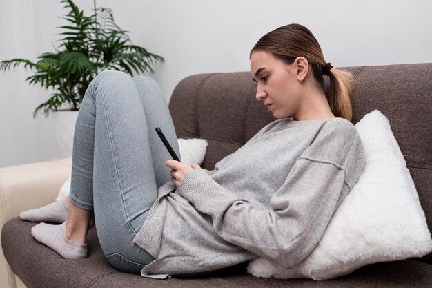 Ragazza giovane con il telefono sul divano