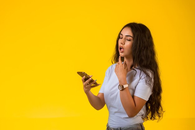 Ragazza giovane guardando il suo telefono e pensando