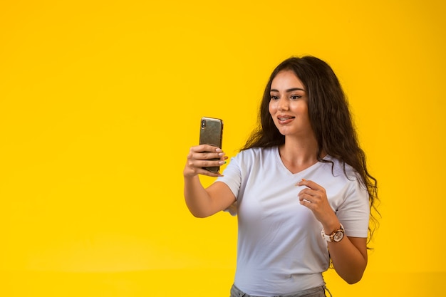 Ragazza giovane guardando il suo telefono e tenendo selfie.